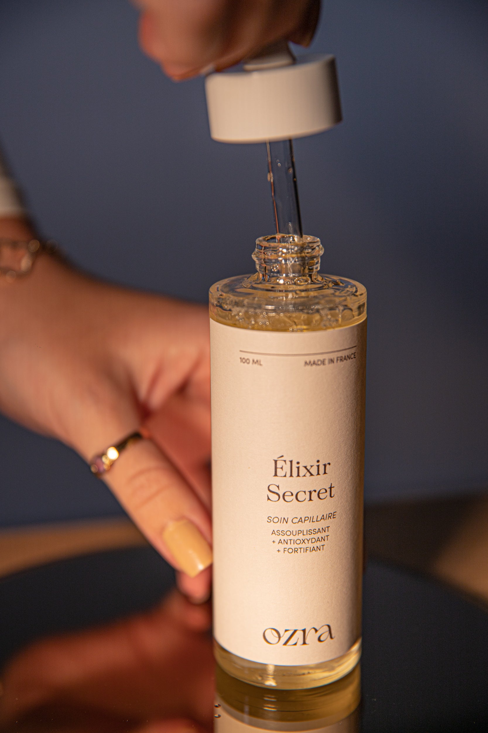 Application de l'huile Élixir Secret sur cheveux bouclés et secs